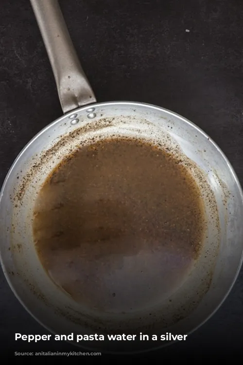 Pepper and pasta water in a silver pan.