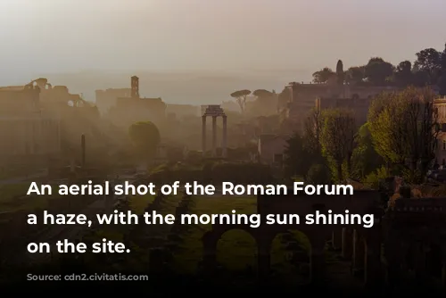 An aerial shot of the Roman Forum in a haze, with the morning sun shining down on the site.