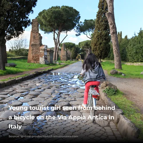 Young tourist girl seen from behind on a bicycle on the Via Appia Antica in Rome, Italy