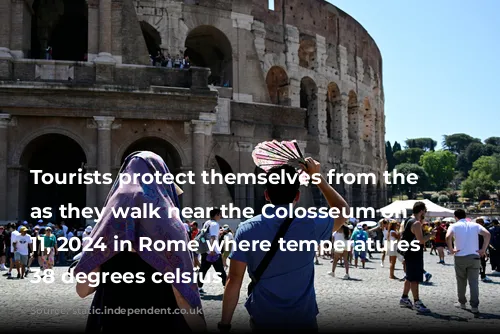 Tourists protect themselves from the sun as they walk near the Colosseum on July 11, 2024 in Rome where temperatures reach 38 degrees celsius