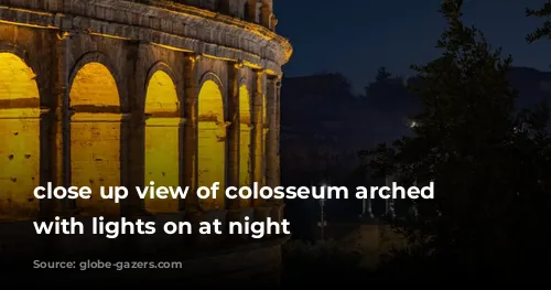 close up view of colosseum arched windows with lights on at night