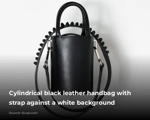 Cylindrical black leather handbag with long strap against a white background 