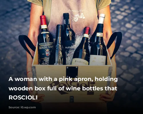 A woman with a pink apron, holding a wooden box full of wine bottles that says ROSCIOLI